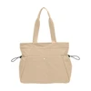 A beige tote bag with yoga mat straps and side pockets. It features two handles and includes a logo.
