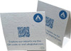 A white seed paper table tent card with a QR code and branding, featuring a textured surface with speckles.