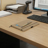 A kraft notebook with a pen rests on a wooden desk beside a computer and document organiser.