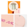 A round makeup mirror with an orange exterior and a pink leather accent. It features a snap closure and branding.
