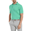 A men's polo shirt in bright green, featuring a collar and short sleeves, paired with grey trousers, includes a logo.