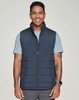 A man wearing a navy blue insulated puffer vest over a light blue shirt, smiling at the camera.