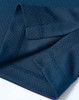 A close-up of a deep navy Jacquard knit fabric with detailed stitching and an edge finish. Features a branding logo.