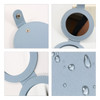 A round folding pocket mirror in light blue, featuring a smooth finish and water droplets on its surface.