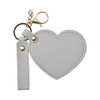 A heart-shaped compact mirror in grey with a keychain attachment and a gold clasp.