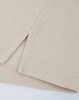 A close-up of a beige cotton/poly pique polo shirt, highlighting the stitched hem and sleeve detail.