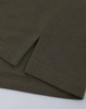 A close-up of a short-sleeved polo in an olive green cotton/poly pique fabric with a stitched hem.