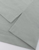 A close-up of a light grey polo shirt featuring short sleeves and a curved hemline. The fabric has a soft texture.