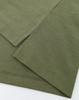 A close-up view of an olive green polo shirt highlighting the fabric texture and stitching details. The garment has a logo.