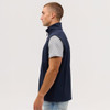 A side view of a navy blue softshell vest with a high collar, worn over a grey T-shirt.