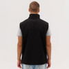 A black softshell vest is displayed, featuring a high collar and a sleek design, with a person wearing it from the back.