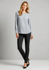 A model wearing grey top and black leggings stands against a plain background. The leggings have a sleek design and a logo.