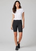 A woman in a white t-shirt and black Luna bike shorts stands confidently. The shorts feature a logo and a fitted style.