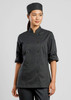 A women's black long sleeve chef jacket with a fitted design and rolled sleeves, accompanied by a matching chef hat.