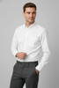 A white long sleeve button-up shirt with a pocket, paired with grey trousers. The shirt features a logo.