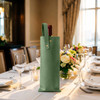 A drink bottle is nestled in an elegant green PU leather wine bag, placed on a beautifully set table.