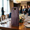 A drink bottle bag in deep burgundy, designed to hold two wine bottles, displayed on a dining table.