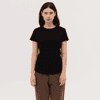 A black women's essential tee with a classic fit, paired with brown pants. The design features a logo on the shirt.