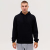 A man wearing a black hoodie with a front pocket, paired with grey sweatpants. The hoodie has a drawstring hood.
