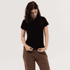 A women's polo shirt in black, featuring a collar and short sleeves, paired with loose-fitting trousers.