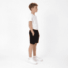 A pair of black youth shorts featured on a child wearing a white t-shirt and white shoes, standing in profile.