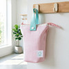 A foldable pink pencil case with a light blue handle, featuring a logo, hanging from a wall hook.