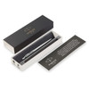 A metal ballpoint pen in brushed stainless steel, presented in a black box with a white interior and a branded card.
