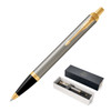 A brushed stainless steel ballpoint pen with gold accents, presented in a black box with branding.