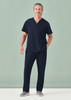 A man wearing navy unisex scrub pants and a matching short-sleeve top, standing against a light green background.
