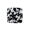 A square acetate vanity mirror featuring a black and white speckled design with a small gold accent.