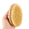 A sisal wooden brush held in a hand, featuring a light wooden base and natural bristles.