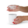 A white coffee cup with a clear lid, held by two hands with red manicured nails.