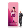 A straight tension fabric display wall in pink featuring a dynamic graphic and a person standing beside it.