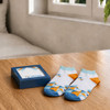 A blue gift box with a square window contains colourful patterned socks in white, blue, and orange.