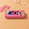 A pink gift box with a rectangular window displays brightly coloured donut-shaped socks inside.