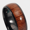 A ceramic ring with a black interior and a textured brown wood grain exterior, featuring a shiny finish.