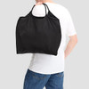 A black nylon shopper bag is being carried on the shoulder of a person wearing a white t-shirt.