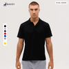 A black polo shirt on a model, featuring a logo and available in multiple colours.