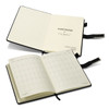 A weekly diary with a sleek black cover and cream pages, featuring a ribbon marker and branding.