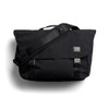 A black messenger bag with a flap, adjustable shoulder strap, and branding label. It features buckle closures and a sleek design.