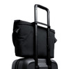 A black messenger bag positioned on top of a wheeled suitcase, featuring a retractable handle.