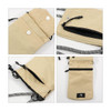 A minimalist crossbody phone bag in beige with a black interior and a patterned strap. It features multiple pockets and fastenings.