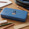 A blue pencil case with a logo sits on a wooden desk surrounded by pencils, an eraser, a ruler, and a notebook.