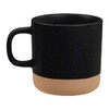 A ceramic coffee mug featuring a black upper body with a speckled finish and a smooth tan lower section. Contains a logo.