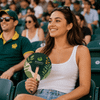 A shaped wooden paper fan with a green and white design held by a smiling woman in casual attire.