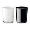 A glass candle set featuring one white and one black candle, each with a wick, in sleek glass containers.