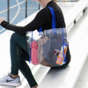 A clear tote bag with blue straps, containing a drink bottle, sunscreen, a hat, and various personal items.