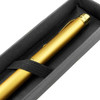 A gold pen rests in a black presentation box secured with an elastic strap. The interior features a soft lining.