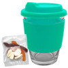 A reusable coffee cup with a turquoise silicone sleeve and a transparent glass body, accompanied by a pack of jelly candies.