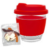A transparent glass coffee cup with a red silicone lid and sleeve, alongside a pack of mixed jelly lollies.